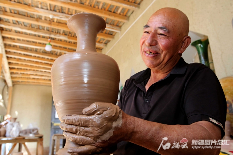 6月19日，英吉沙縣芒辛鎮(zhèn)恰克日庫依村土陶非遺傳承人阿卜杜熱合曼·麥麥提敏在欣賞剛制作的土陶作品。石榴云/新疆日?qǐng)?bào)記者 蔡增樂 攝